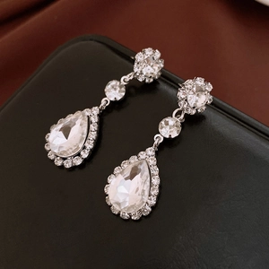 Detailed view of teardrop crystal drop earrings with sparkling stones on a dark background