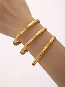 Close-up of three layered 18K gold-plated snake bone textured bangles on a model's wrist
