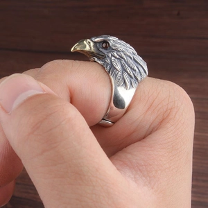 Vintage eagle ring with silver body, gold beak and red eye on a dark wood background