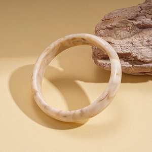 Dettaglio di un bracciale rigido in resina ambrata marmorizzata su pietra naturale