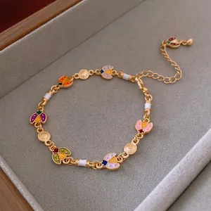 Golden bracelet with colorful enamel ladybug charms and white beads on grey velvet