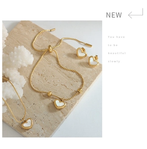 Close-up of heart-shaped gold jewelry set with white shell inlay on textured stone