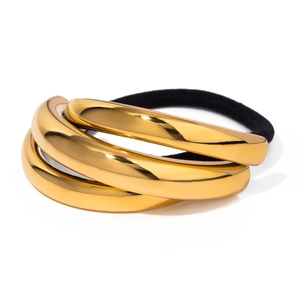 Detailed view of three polished gold stainless steel rings on a black elastic hair tie