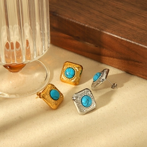 Boucles d'oreilles vintage en acier titane doré et argenté avec turquoise sur fond texturé