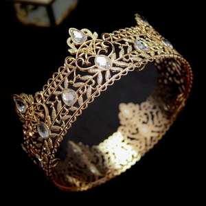 Close-up of luxury gold royal crown with intricate hollow floral patterns and sparkling crystals