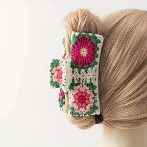 Detail of floral crochet hair claw clip with rose and green leaves on knitted fabric