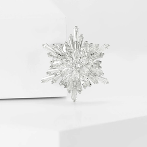 Close-up of a silver snowflake brooch with sparkling cubic zirconia on a white stand