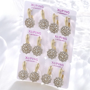 Detail view of six pairs of gold-plated cluster stud earrings on a white jewelry card