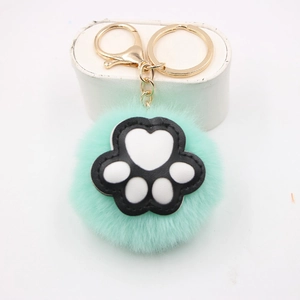 Detail of mint green plush ball keychain with black cat paw print and gold metal clasp