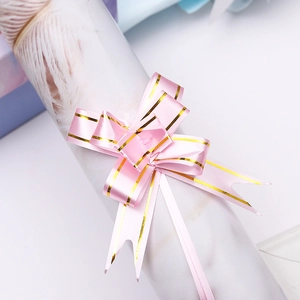 Macro shot of pink plastic gift ribbon bow with gold edges for festive gift packaging