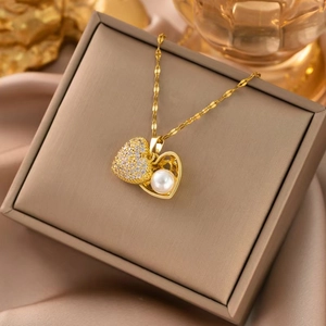Detailed close-up of a 18k gold heart-shaped pendant with white pearls and zircons