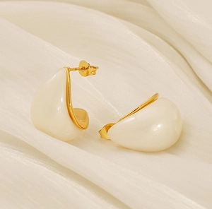 Detailed macro view of teardrop cream enamel earrings with 18K gold plated steel frame