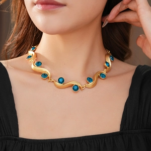 Close-up of vintage gold wave necklace set with brilliant round blue gemstones