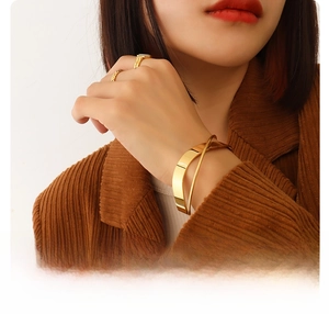 Close-up of 18k gold plated titanium steel crossover bangle and ring set on model