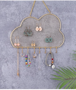 Close-up of cloud-shaped golden metal grid jewelry rack mounted on a grey wall