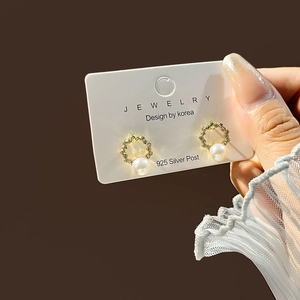 Detail of geometric pearl earrings with rhinestones and 925 silver post on jewelry card