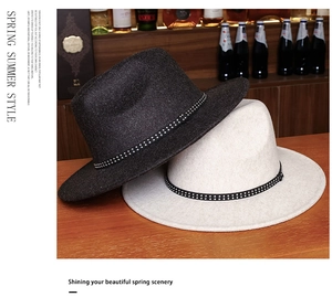 Detail of black and beige wide brim fedora hats with silver rivet bands on a wood surface