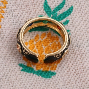 Close-up of gold-plated ring featuring colorful gemstones and black enamel detailing