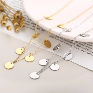 Flat lay of gold and silver stainless steel necklaces with polished round coin pendants
