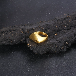 Macro view of gold triangle stainless steel ring on black textured stone surface