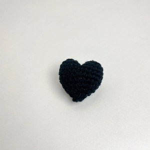 Detailed close-up of a handmade black crochet heart brooch crafted from premium yarn fabric