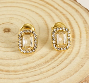 Detailed view of double-layer gold square stud earrings with zircons on a wooden base