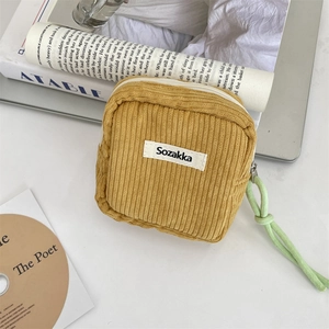 Detail of ginger corduroy makeup bag featuring a zip closure and woven brand label