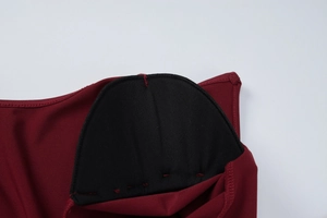 Dettaglio ravvicinato delle imbottiture nere e delle cuciture sul vestito bordeaux