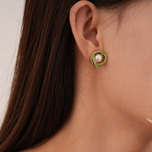 Close-up of vintage gold stud earring featuring green rhinestones and a white pearl