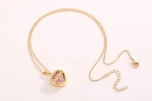 Detailed view of heart-shaped gold necklace with pink stone and MOM engraving