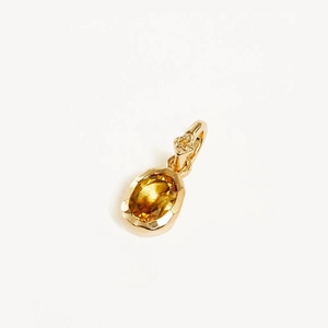 Detail of gold pendant with oval yellow gemstone and polished link on white background