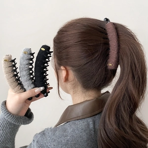 Detail of plush knit banana hair clips in beige, grey, black and coffee colors