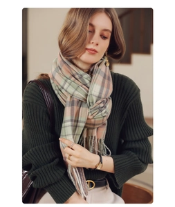 Detail of soft plaid scarf with tassels in pink and olive on a female model in winter outfit