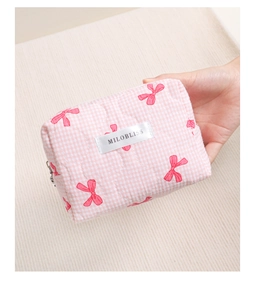Nahaufnahme der rosa gesteppten Kosmetiktasche mit roten Schleifen und Markenlabel