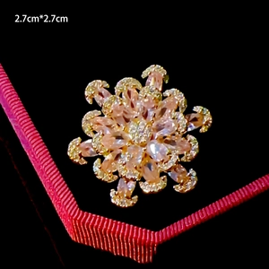 Macro detail of 2.7cm gold floral brooch with emerald green teardrop and pink crystals