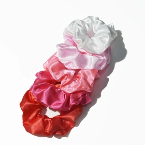 Set of four satin hair scrunchies in white, pink and red colors on white background