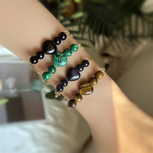 Close-up of heart-shaped natural stone bracelets with gold chains on model's wrist