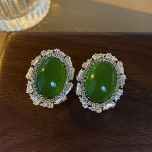 Detail shot of vintage green oval acrylic stud earrings with baguette zirconia on wood