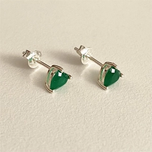 Macro detail of heart-shaped green zircon studs with 925 silver three-prong setting