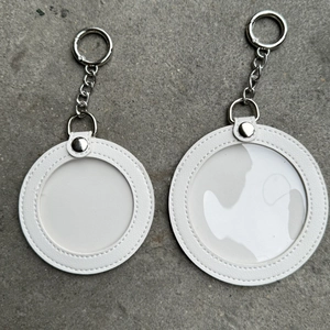 Detail view of round white leather badge holder keychains with clear PVC window