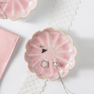Close-up of pink lotus ceramic jewelry tray holding golden rings and necklaces