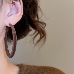 Gros plan sur des créoles en velours marron portées avec un tricot d'hiver