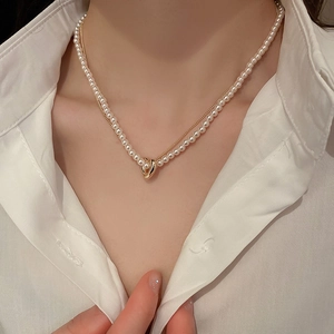 Detail of a double-layered gold heart pendant necklace with elegant white pearls