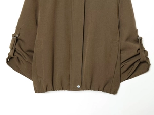 Detail of dark brown bomber jacket featuring elastic hem and metal ring on sleeve cuff
