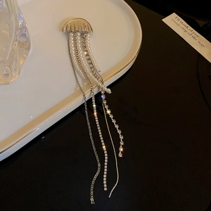 Macro shot of silver jellyfish brooch with pearl tassels and rhinestones on a ceramic dish