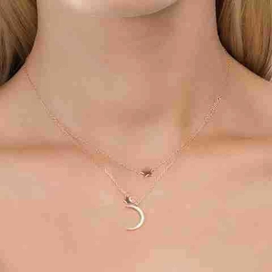 Detail of double-layer S925 silver necklace with moon and star pendants in rose gold finish