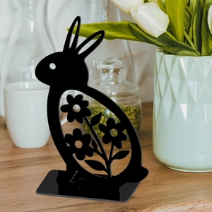 Detail of black Easter bunny silhouette with hollow floral patterns on a wooden table