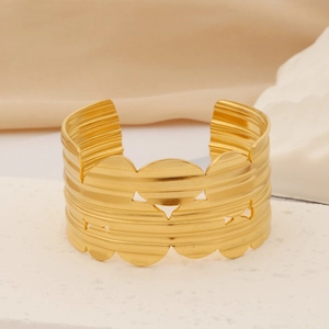 Detailed close-up of wide gold stainless steel cuff featuring geometric cutouts and texture