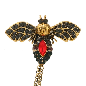 Detail of vintage bee brooch with colorful crystals and golden double hanging chains
