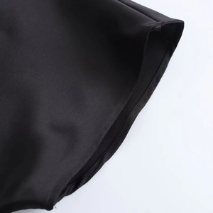 Detailansicht des schwarzen Satin-Midikleids mit hochwertigen Nähten und Stoffstruktur